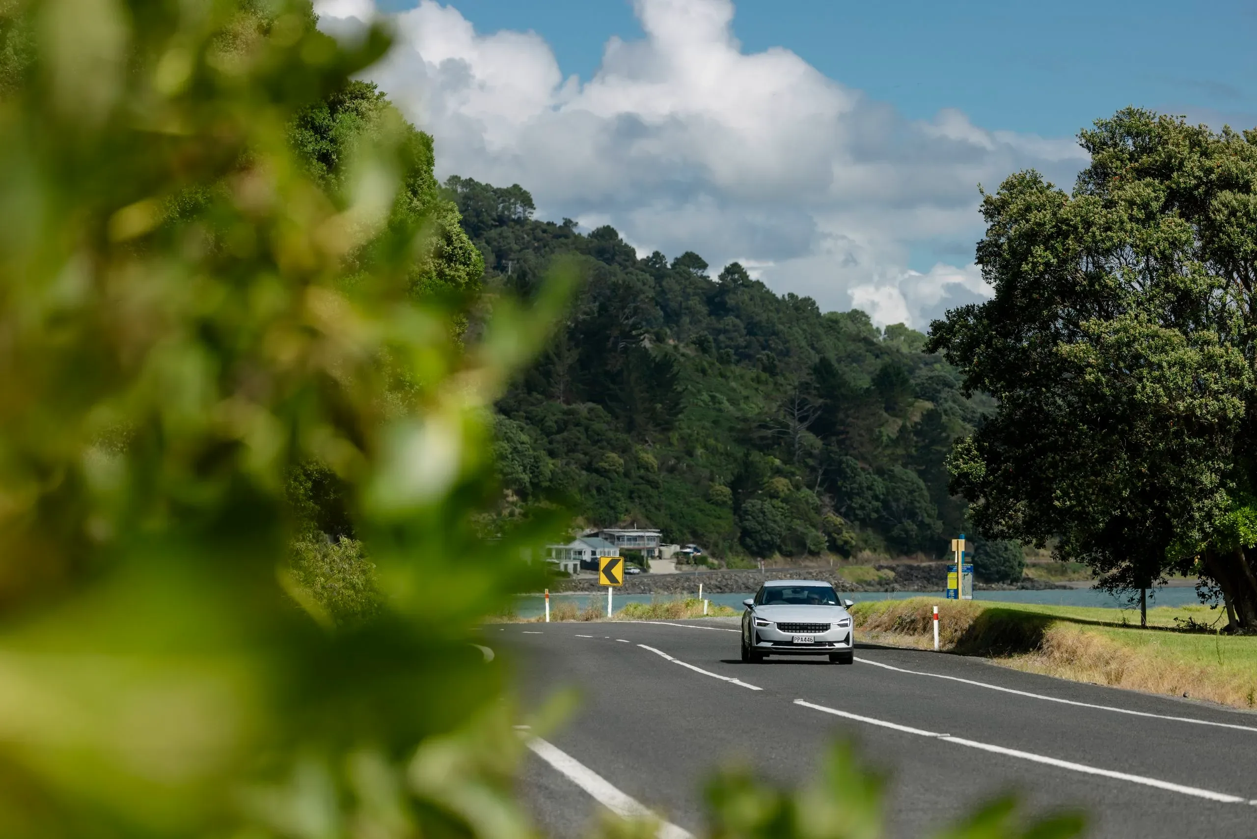 Car driving along coastal road at Thornton Bay Coromandel Peninsula on North Island New Zealand itinerary