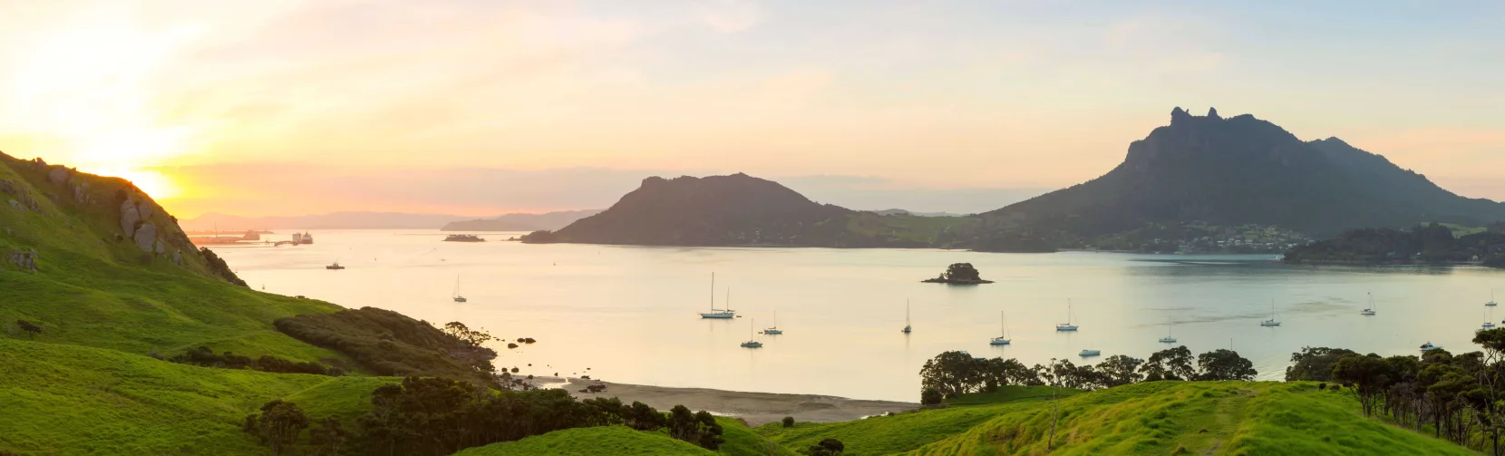 Sunset over Whangārei Harbour with yachts anchored in calm waters and green hills in Northland, New Zealand