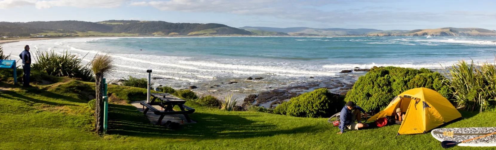 Camping by the beach at Curio Bay Tumu Toka with ocean waves, picnic area and coastal scenery in the Catlins, Southland New Zealand