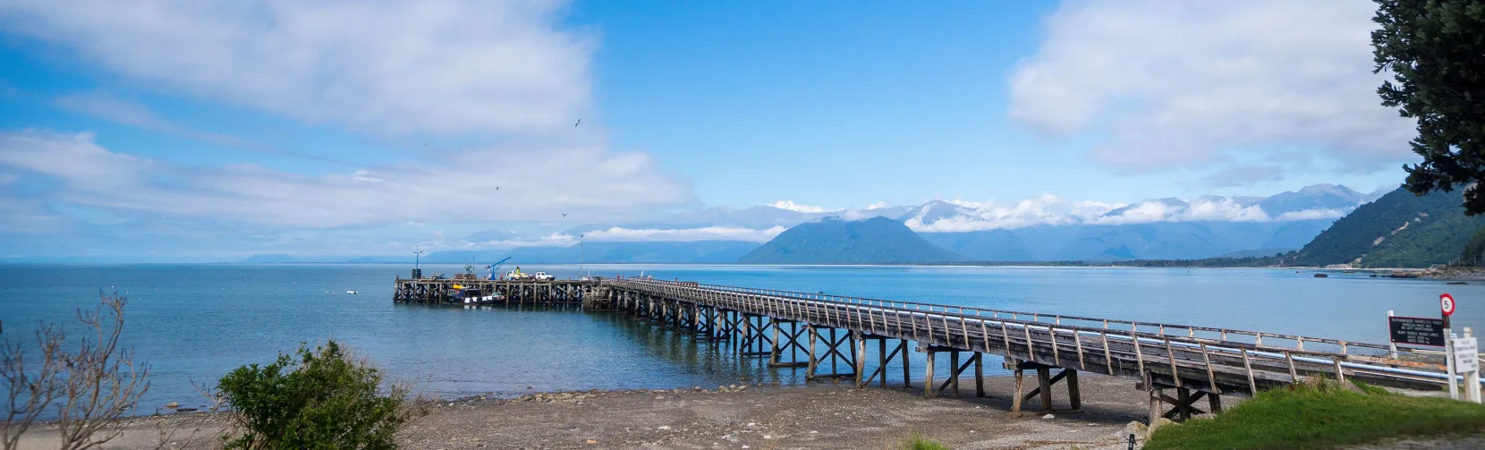 Wooden wharf stretching into the sea at Jackson Bay, a small fishing port near Haast on the West Coast of New Zealand’s South Island