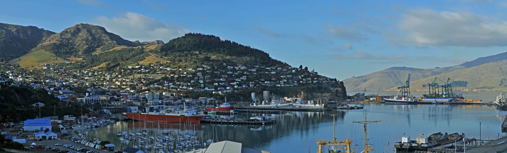 Panoramic view of Lyttelton Port with boats, shipping docks and surrounding hills near Christchurch in Canterbury, New Zealand