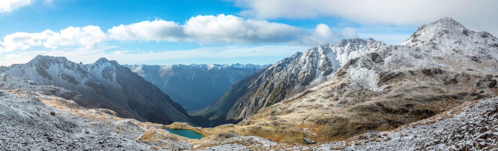 Snow-dusted mountains surrounding an alpine tarn in Nelson Lakes National Park, South Island New Zealand, with sweeping panoramic views