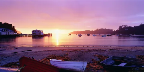 Sunset over Halfmoon Bay in Oban with boats anchored in the harbour on Stewart Island Rakiura, Southland New Zealand