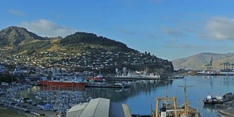 Panoramic view of Lyttelton Port with boats, shipping docks and surrounding hills near Christchurch in Canterbury, New Zealand