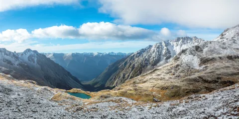 Snow-dusted mountains surrounding an alpine tarn in Nelson Lakes National Park, South Island New Zealand, with sweeping panoramic views