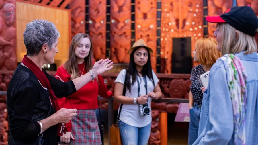 Visitors exploring Māori cultural exhibits inside Auckland Museum, a renowned neoclassical landmark in New Zealand.
