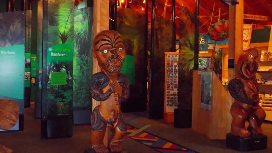 Interior of Auckland Museum displaying Maori wood carvings and vibrant rainforest exhibits