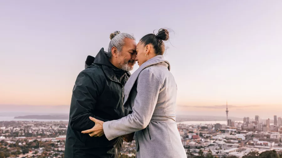 Couple performing hongi with Auckland city in background