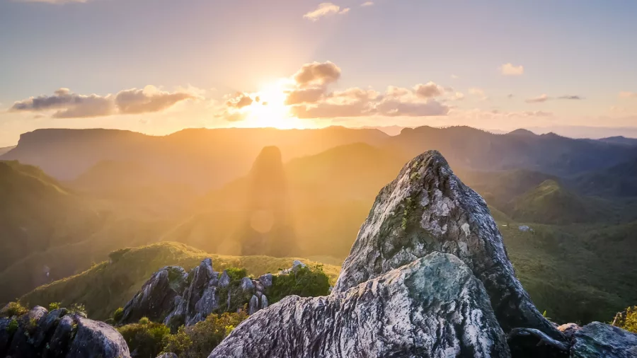 Fiery sunset over The Pinnacles summit in the Coromandel with forested ridges below