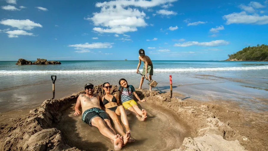 Family relaxing in a handmade thermal pool at Hot Water Beach, Coromandel