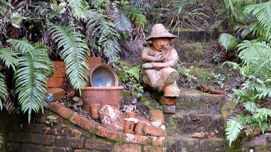 Clay sculpture and pottery displayed amongst ferns at Driving Creek Railway