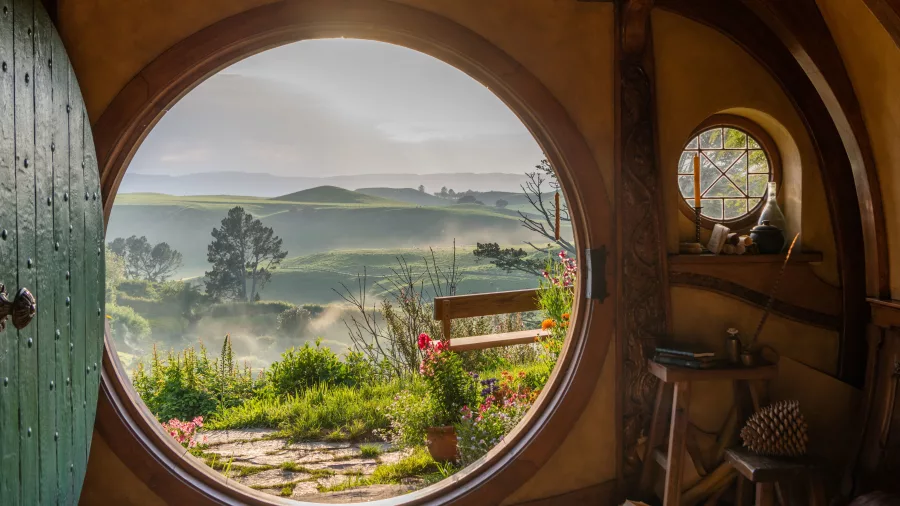 View from inside a Hobbit Hole looking out at the rolling hills and garden at Hobbiton