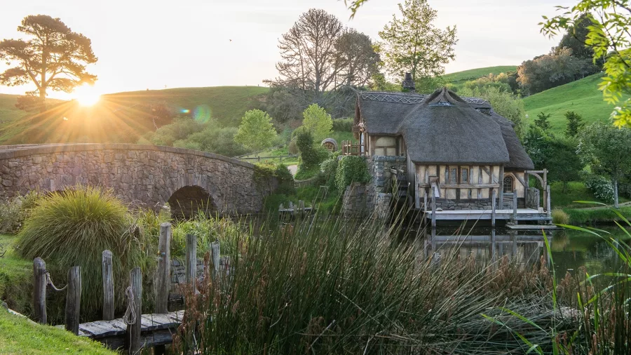 Stone bridge and The Mill at Hobbiton at sunset with lush green hills