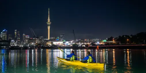 Auckland City Lights Night Kayak Tour on Waitemata Harbour with Sky Tower and city skyline illuminated at night