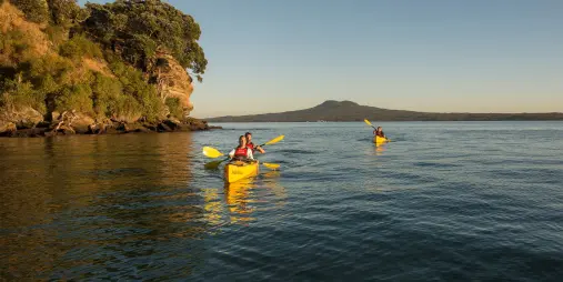 paddlers sea kayaking along Rangitoto Island coastline on Waitemata Harbour