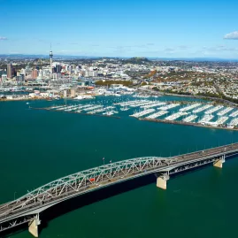 Aerial view of Auckland Harbour Bridge with city skyline and marina in the background