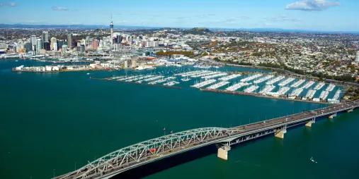 Aerial view of Auckland Harbour Bridge with city skyline and marina in the background