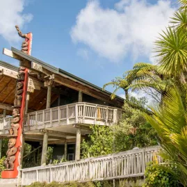 Arataki Visitor Centre with Māori carving and native bush in Waitākere Ranges