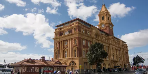 Historic Auckland Ferry Building with cyclists passing along Quay Street