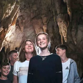Family group admiring limestone formations inside Waitomo Caves during a guided walking tour