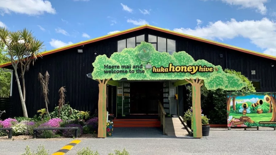 Exterior entrance of Huka Honey Hive with welcome sign and gardens in Taupō, New Zealand
