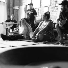 Participants seated on mats during a traditional kava ceremony in a welcoming Auckland venue, with music and conversation enhancing the cultural experience.