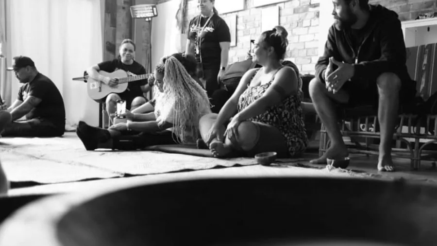 Participants seated on mats during a traditional kava ceremony in a welcoming Auckland venue, with music and conversation enhancing the cultural experience.