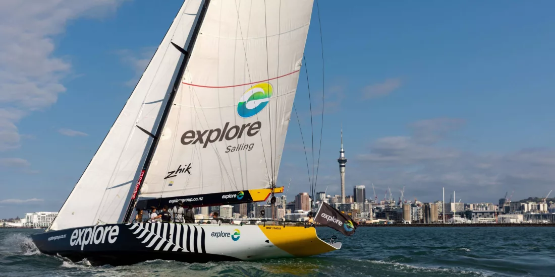 The America's Cup yacht NZL68 sailing across Auckland Harbour with the city skyline in the background