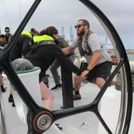 Crew members working together on the deck of a racing yacht, adjusting sails during a regatta