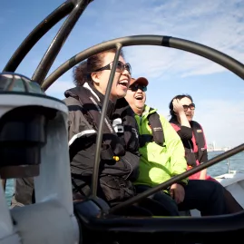 A group of passengers laughing and enjoying a sailing experience on a yacht