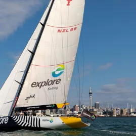 The America's Cup yacht NZL68 sailing across Auckland Harbour with the city skyline in the background