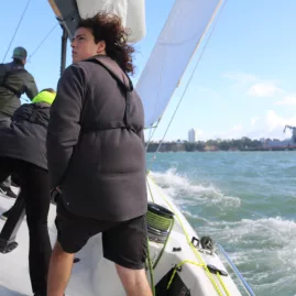 Crew members actively adjusting positions on a racing yacht as it cuts through the waves