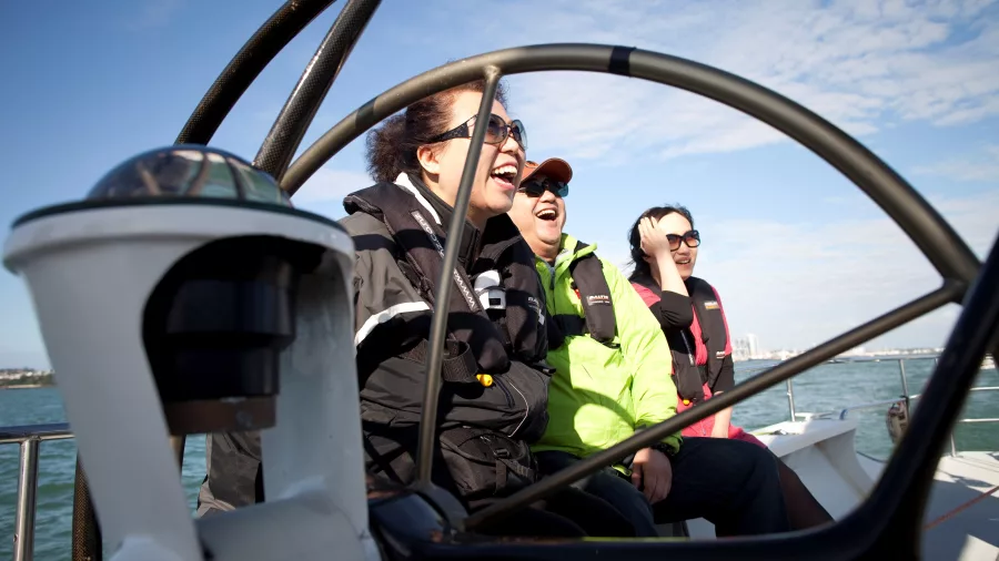 A group of passengers laughing and enjoying a sailing experience on a yacht