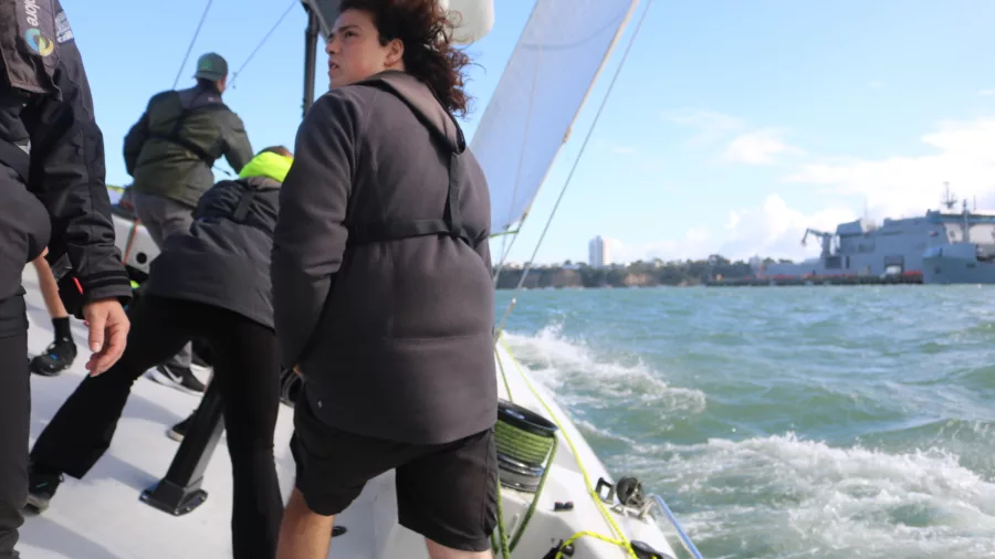 Crew members actively adjusting positions on a racing yacht as it cuts through the waves