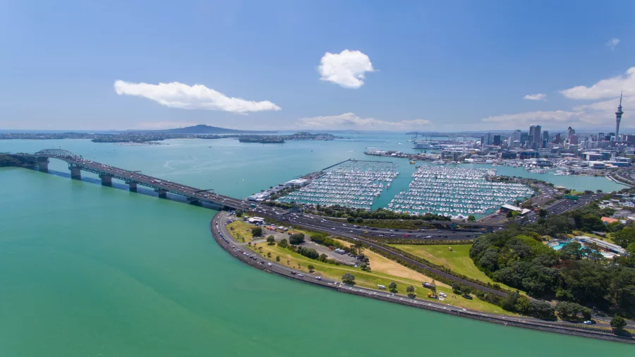 A stunning aerial view of Auckland Harbour Bridge, the marina, and the city skyline on a clear day