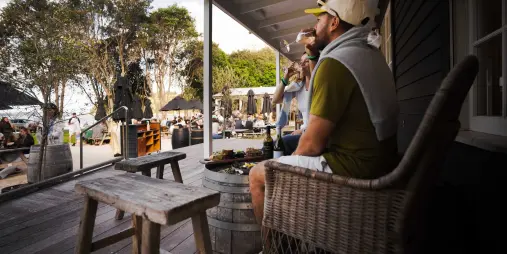Couple enjoying wine and food on an outdoor deck at a Waiheke Island winery.