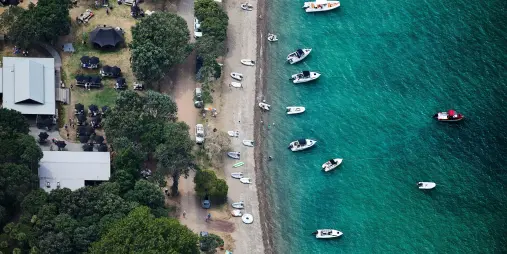 Aerial view of Man O' War Bay on Waiheke Island with boats anchored offshore.