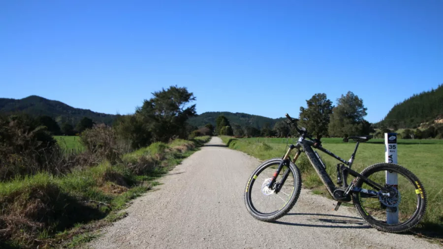 E-bike resting beside a marker post on the open gravel path of the Twin Coast Cycle Trail