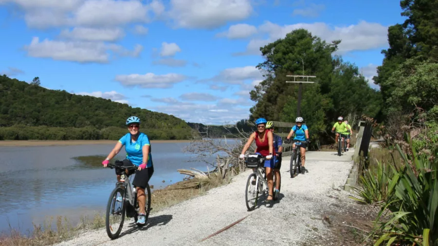 Cyclists riding beside the river near Hokianga Harbour on the Twin Coast Cycle Trail