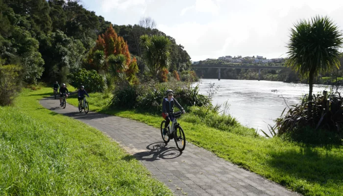 E-bike group tour riding beside the Waikato River with a bridge in the background