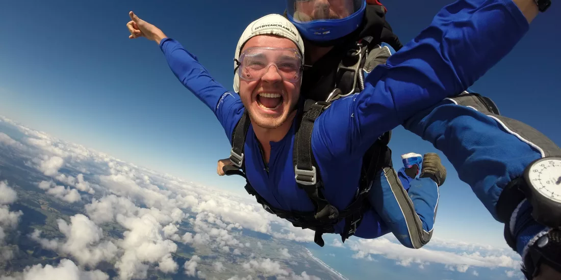 Happy man enjoying a tandem skydive over Auckland’s east and west coastlines