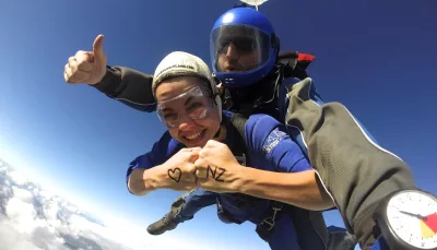 Skydiver with ‘I ❤️ NZ’ written on hands during tandem jump over Auckland