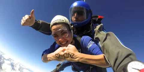 Skydiver with ‘I ❤️ NZ’ written on hands during tandem jump over Auckland