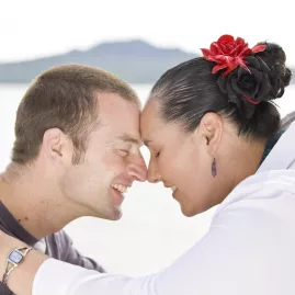 Smiling couple exchanging a hongi with Rangitoto Island in the background