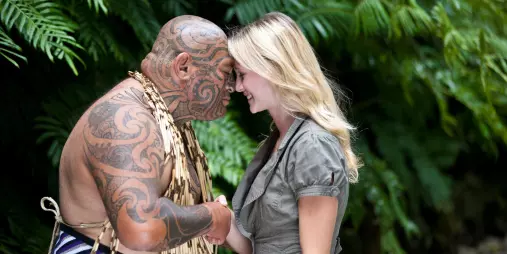 Māori man and visitor sharing a traditional hongi greeting in native forest setting
