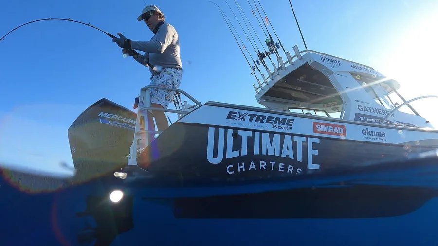 Fisherman fighting a fish on the back of Ultimate Charters boat
