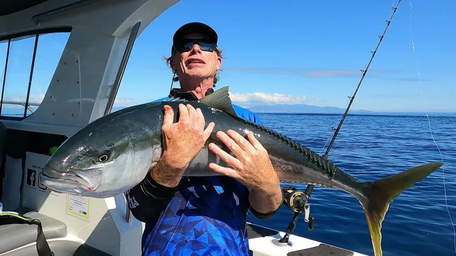 Angler proudly holding a giant kingfish on board Ultimate Charters