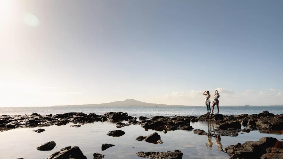 Women exploring Takapuna Coastal Walkway with views of Hauraki Gulf and Rangitoto Island