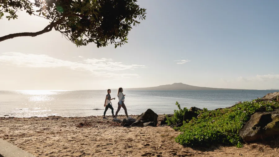 Women walking on beach with Rangitoto Island view