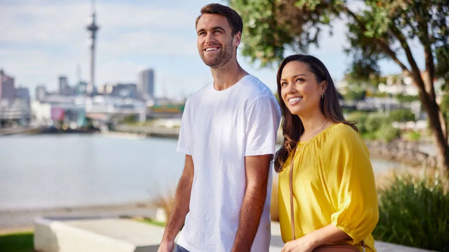 Couple walking around Westhaven Marina with Auckland City skyline in the background